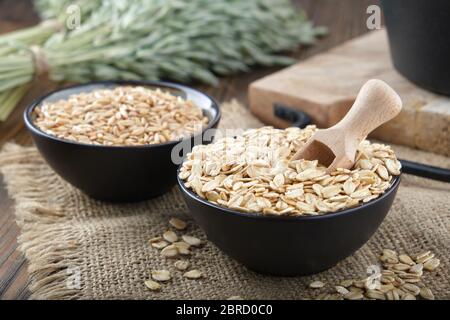 Bols de grains d'avoine et flocons d'avoine, oreilles d'avoine verte sur une table de cuisine en bois. Banque D'Images