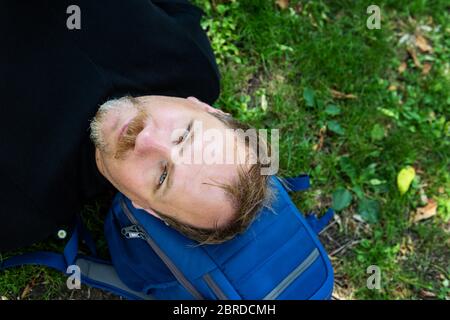 Portrait d'un homme beau sur l'herbe. Un homme heureux se détendant dehors allongé sur l'herbe Banque D'Images