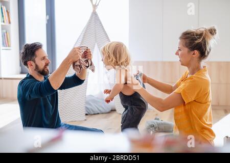 Jeune famille avec un petit enfant à l'intérieur dans la chambre à coucher s'habiller. Banque D'Images