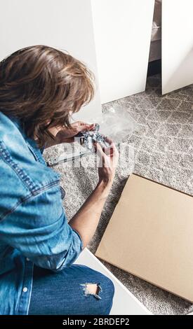 Jeune homme déballage boîte avec meubles de bricolage pour la maison Banque D'Images