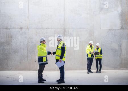 Un groupe d'ingénieurs se tenant sur le chantier, en serrant la main. Banque D'Images