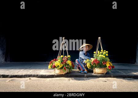 Hoi an Ancient Town, province de Quang Nam, Vietnam - 10 mai 2020: Photo d'une femme qui vend des fleurs sur une paire de cadres en bambou dans la ville antique de Hoi an, Q Banque D'Images