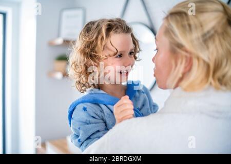 Une petite fille mignonne avec une mère méconnue dans la salle de bains à l'intérieur à la maison. Banque D'Images