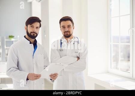 Deux médecins praticiens avec un presse-papiers debout dans un bureau de clinique.médecine de soins de santé.les travailleurs médicaux attendent les patients sur le lieu de travail. Ajuster Banque D'Images
