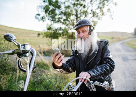 Un homme âgé voyageant à moto en campagne, prenant le selfie. Banque D'Images