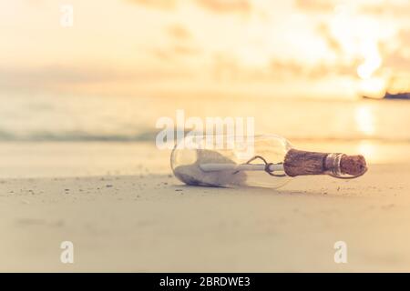 Message dans la bouteille lavée à terre contre le coucher du soleil. Coucher de soleil tropical sur la plage. Castaway, solitude, concept perdu Banque D'Images
