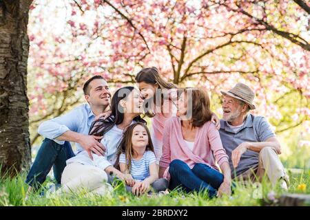 Trois générations de famille assis à l'extérieur dans la nature de printemps. Banque D'Images