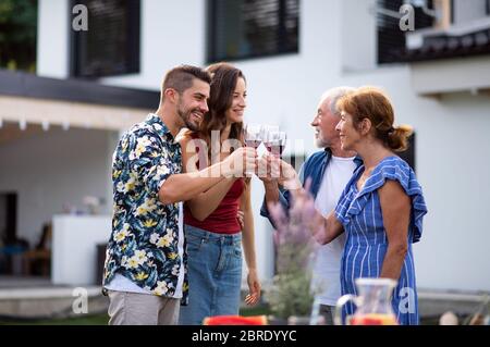 Portrait de personnes avec du vin à l'extérieur sur le barbecue de jardin familial. Banque D'Images