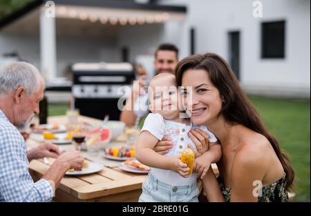 Portrait de famille étendue assis à table à l'extérieur sur le barbecue de jardin. Banque D'Images