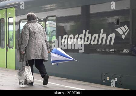 15 mai 2020, Hambourg: Une femme avec un parapluie marche le long d'un train de la NBE nordbahn Eisenbahn-Verwaltungsgesellschaft mbH, qui est garée dans la gare Altona. La nordbahn est placée sous l'égide des associations de transport de Hambourg (HVV) et du Schleswig-Holstein (NAH.SH). Photo : marques de bodo/dpa/marques de bodo Banque D'Images