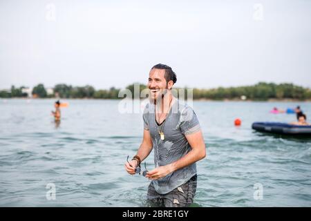 Jeune homme humide s'amusant au festival d'été, debout dans le lac. Banque D'Images