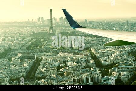 L'avion survole Paris, France. Vue panoramique aérienne de la tour Eiffel depuis la fenêtre de l'avion. L'aile de l'avion au-dessus des rues de Paris. Concept de TR air Banque D'Images