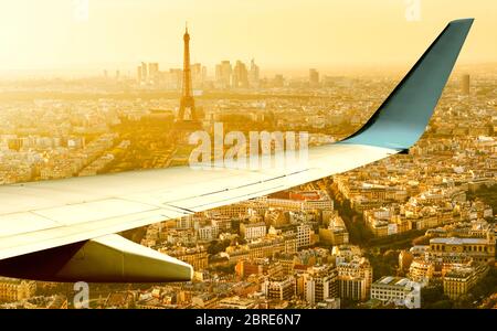 L'avion survole Paris en soirée d'été, en France. Vue panoramique aérienne de la tour Eiffel depuis la fenêtre de l'avion. L'aile de l'avion au-dessus des rues de Paris Banque D'Images