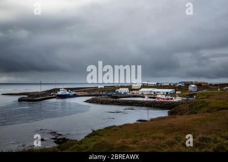 le port de l'île de grimsey dans le nord de l'islande, au large du cercle arctique. Le ciel est chargé de nuages et un bateau amarré attend les touristes Banque D'Images