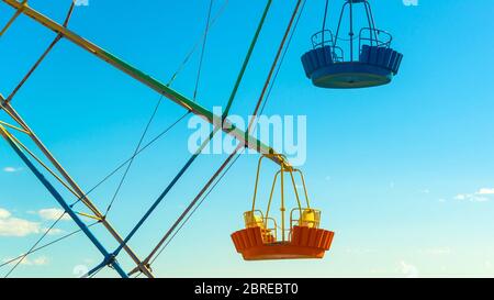 Les cabines de Ferris se rapprochent sur fond bleu ciel. Détail de la grande roue colorée dans le parc d'attractions. Concept de vacances et entrée des enfants Banque D'Images