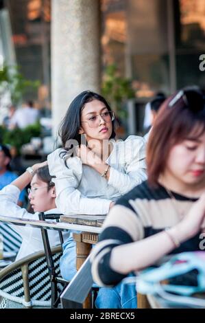 Une jeune femme thaïlandaise élégante se détend dans un restaurant sur le balcon de l'Iconcierge Shopping Bangkok Thailand. Banque D'Images