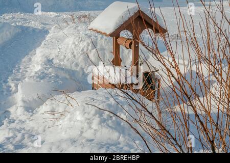 Paysage de village d'hiver. Puits en bois avec un treuil dans les dérives. Une extraction d'eau ancienne et rare device.frosty jours Banque D'Images