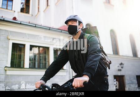 Livreur avec masque facial et vélo en ville. Banque D'Images