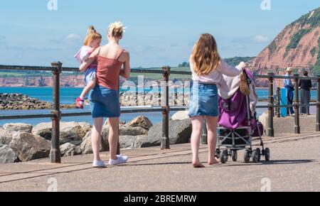 Sidmouth, East Devon, Royaume-Uni. 21 mai 2020. Météo au Royaume-Uni : une jeune famille marche le long de l'esplanade par un temps ensoleillé et extrêmement chaud dans la pittoresque ville de regency de Sidmouth. Le soleil brûlant devrait continuer dans le week-end des vacances en banque. Crédit : DWR/Alamy Live News Banque D'Images