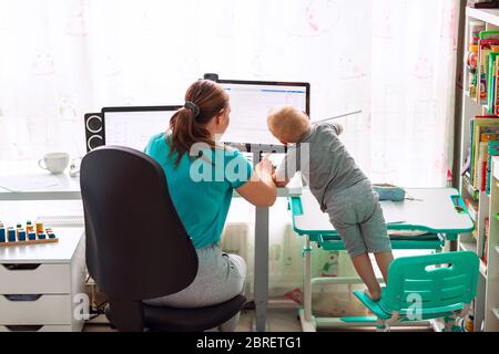 Mère avec enfant essayant de travailler de la maison pendant la quarantaine. Rester à la maison, travailler à domicile concept pendant la pandémie de coronavirus Banque D'Images