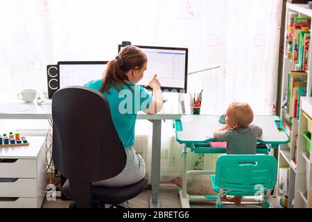 Mère avec enfant essayant de travailler de la maison pendant la quarantaine. Rester à la maison, travailler à domicile concept pendant la pandémie de coronavirus Banque D'Images