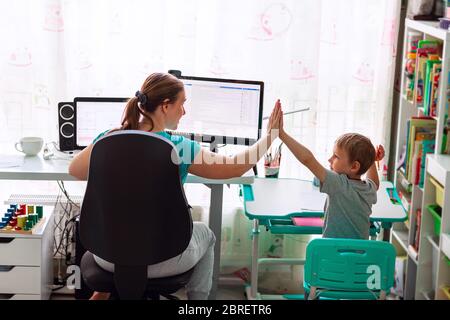 Mère avec enfant essayant de travailler de la maison pendant la quarantaine. Rester à la maison, travailler à domicile concept pendant la pandémie de coronavirus Banque D'Images