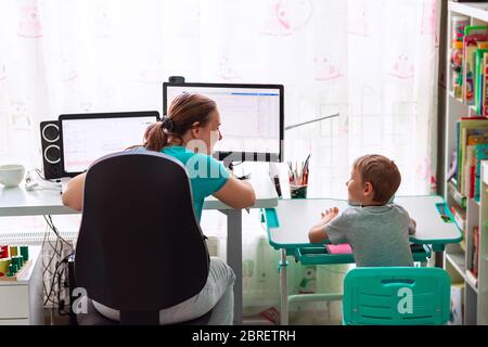 Mère avec enfant essayant de travailler de la maison pendant la quarantaine. Rester à la maison, travailler à domicile concept pendant la pandémie de coronavirus Banque D'Images