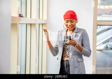 une jeune femme d'affaires noire se sent excitée et surprise en regardant son téléphone mobile Banque D'Images