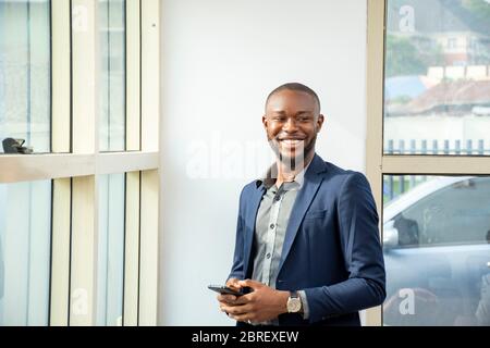 portrait d'un jeune homme d'affaires africain portant un costume souriant et en train de regarder heureux Banque D'Images