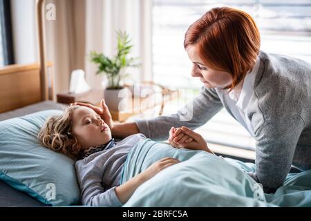 Mère soignante rendant visite à une petite fille fille au lit à l'hôpital. Banque D'Images