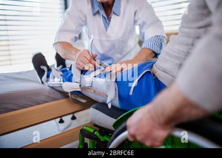 Travailleur de santé méconnaissable et patient sénior paralysé à l'hôpital. Banque D'Images