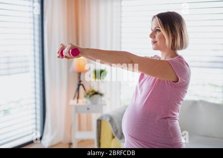 Portrait de la femme enceinte à l'intérieur à la maison, faisant de l'exercice. Banque D'Images