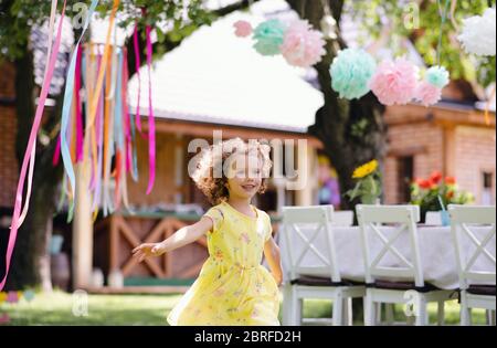 Petite fille courir à l'extérieur dans le jardin en été, concept de célébration d'anniversaire. Banque D'Images