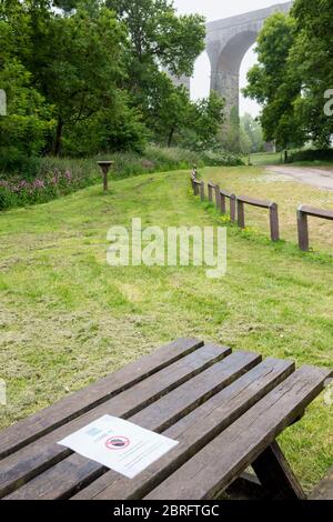 Avis du Conseil agrafé à une table de pique-nique dans un parc de campagne vide interdisant l'utilisation de la table en raison des règlements de santé et de sécurité Covid 19. Banque D'Images