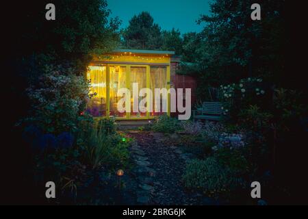 Abri de jardin ou atelier arrière avec lumières allumées en soirée Banque D'Images