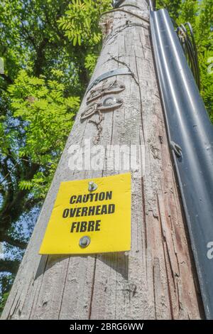 Panneau d'avertissement jaune sur le poteau du réseau téléphonique avertissement du câble à fibre optique aérien. Métaphore rural large bande, large bande dans les zones rurales, rural B/B. Banque D'Images