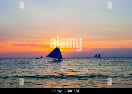 Bateau philippin traditionnel à l'idyllique plage de sable blanc de l'île Boracay à Philiberines au coucher du soleil Banque D'Images