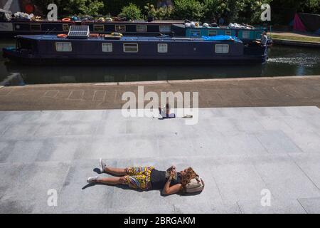 Une femme baigne de soleil à côté du canal Regents à Kings Cross, Londres, tandis que les gens affluent vers les parcs et les plages avec des mesures de verrouillage assouplies. Banque D'Images