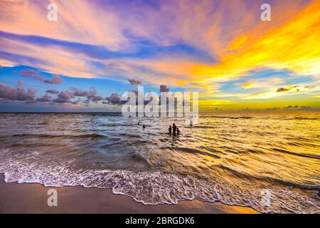 les gens nageant en mer à une plage au coucher du soleil, naples, floride, usa Banque D'Images