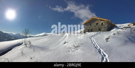 chalet alpin traditionnel au sommet de la montagne enneigée sous le soleil levant dans le ciel Banque D'Images