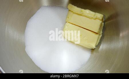 Gros plan de morceaux de beurre et de sucre blanc, dans un bol à mélanger en métal. Banque D'Images