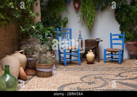 Magnifique patio andalou avec plantes, chaises bleues, table en bois et vases placés sur un sol en mosaïque. Cordoue, Andalousie, Espagne. Voyages et tou Banque D'Images