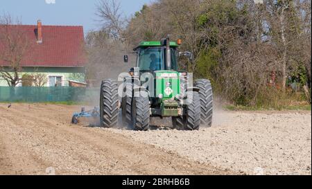 Nagybajcs Hongrie 04 04 2020: Un grand tracteur John Deere 4755 moderne avec roues doubles va dans le champ. Le tracteur cultive le sol. Banque D'Images