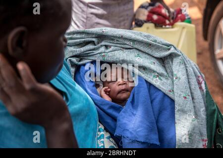 Gulu, région du Nord, Ouganda. 13 mai 2020. Une femme porte son nouveau-né à l'extérieur de l'hôpital régional de Gulu pendant la crise du coronavirus. Les groupes de défense des droits des femmes affirment que l'interdiction de transport liée au coronavirus en Ouganda a entraîné une augmentation des décès maternels en raison des problèmes que les femmes enceintes ont tenté d'accéder aux soins de santé d'urgence. Crédit : Sally Hayden/SOPA Images/ZUMA Wire/Alay Live News Banque D'Images