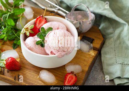 Crème glacée bio aux fraises maison. Boules de glace à la fraise avec feuilles de menthe sur une table en pierre ou en ardoise. Banque D'Images
