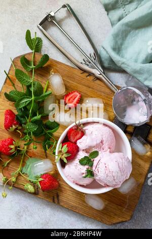 Crème glacée bio aux fraises maison. Boules de glace à la fraise avec feuilles de menthe sur une table en pierre ou en ardoise. Banque D'Images