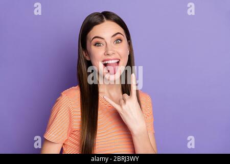 Gros plan photo de la femme attrayante folle funky longue brun droit coiffure montrer doigt cornes coller langue porter décontracté orange rayé t-shirt Banque D'Images