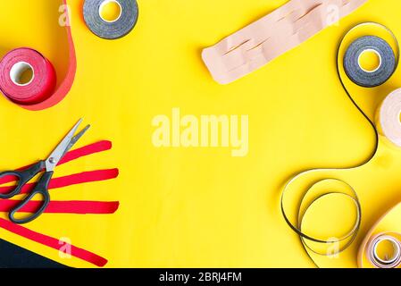 Kit pour kinésiologie traitement de bande de physio spécial rouleaux de différentes couleurs et ciseaux pour couper sur un fond jaune, espace de copie Banque D'Images