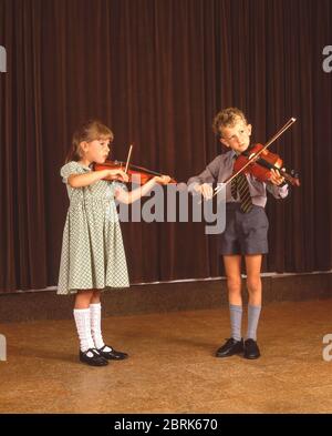 Jeune fille et jeune garçon de première classe jouant des violons dans un orchestre d'école, Surrey, Berkshire, Angleterre, Royaume-Uni Banque D'Images