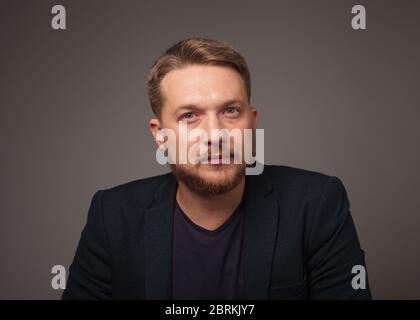 Beau homme sur fond sombre regardant la caméra. Banque D'Images